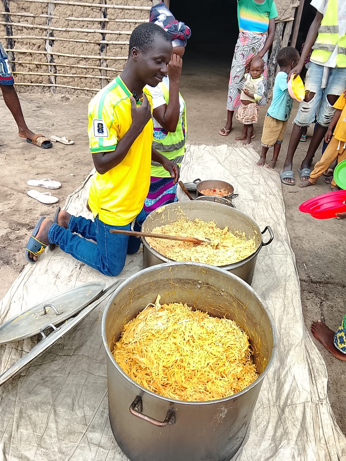Ajude África ajoelhado ao lado das panelas, antes da distribuição.